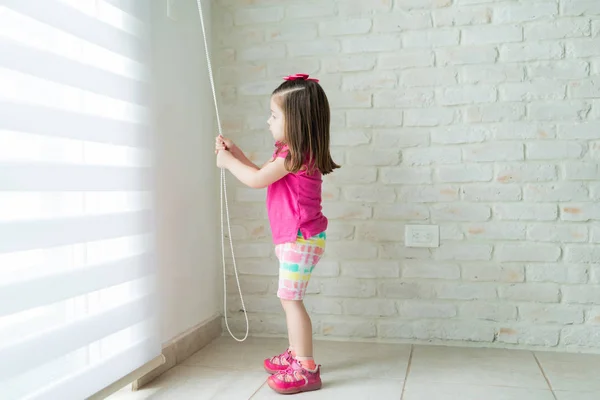 Vista Lateral Una Niña Pequeña Abriendo Persianas Ventana Casa — Foto de Stock