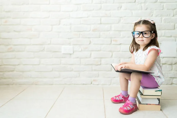 Smart Kleinkind Mit Brille Sitzt Auf Gestapelten Buch Wohnzimmer Hause — Stockfoto