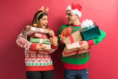 Kırmızı arka plan karşı Noel hediyeleri tutan neşeli genç çift