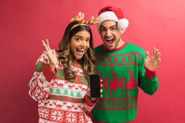 Şaşırttı İspanyol erkek arkadaşı ve kız arkadaşı düz arka plan karşı mobil tutarak