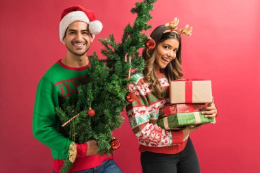 Mutlu genç çekici güzel çift Noel ağacı ve stüdyoda hediyeler taşıyan