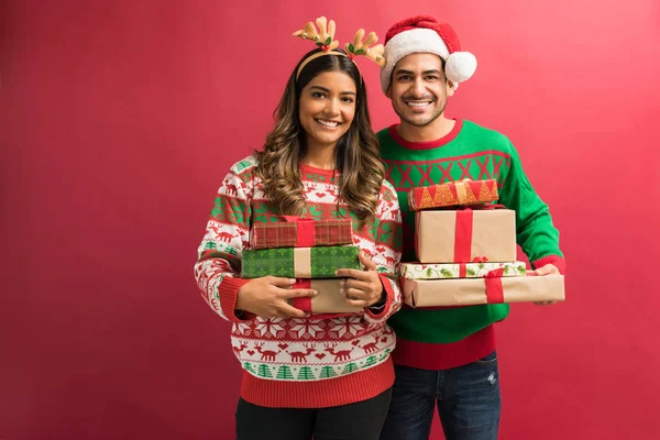 Gülümseyen genç Latin çift stüdyoda göz teması yaparken hediyeler ile ayakta