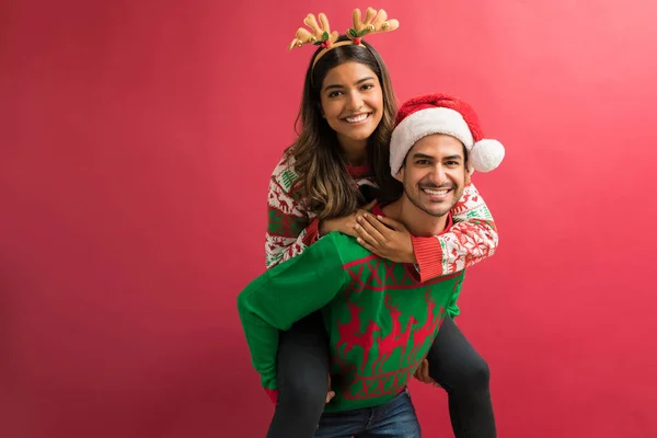 Cheerful Boyfriend Giving Piggyback Girlfriend Christmas Celebration Plain Background — Stock Photo, Image