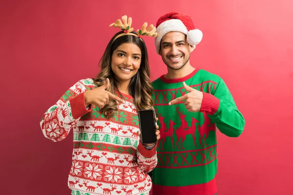 Stüdyoda izole göz teması yaparken akıllı telefon işaret Muhteşem genç Latin çift