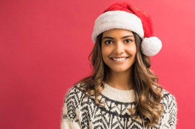 Kırmızı arka plan karşı Noel şapkası giyen çekici genç kadın esmer Portresi