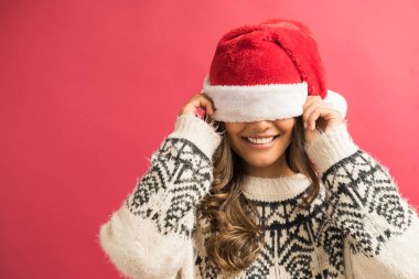 Uzun kahverengi saçlı gülen genç kadın düz arka plan karşı şapka ile gözleri kaplayan