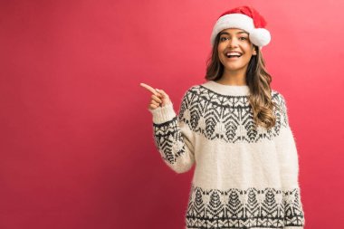 Kendinden emin muhteşem Latin kadın gülümseyen ve stüdyoda izole kopya alanı işaret