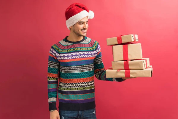 Happy Latin Male Looking Stack Gifts While Standing Plain Background — Stock Photo, Image