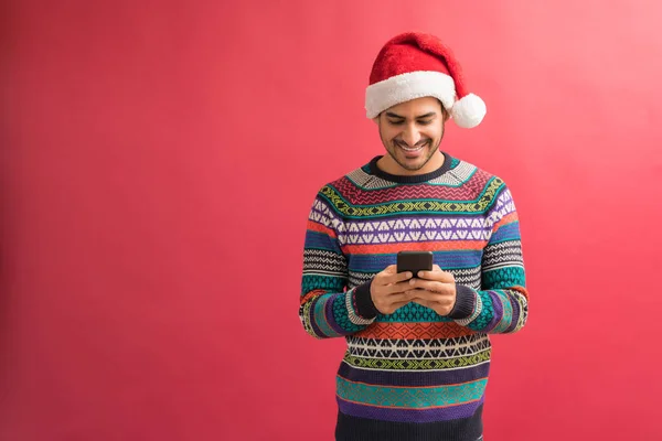 Happy Latin Man Text Messaging Smartphone While Celebrating Xmas Plain — Stock Photo, Image