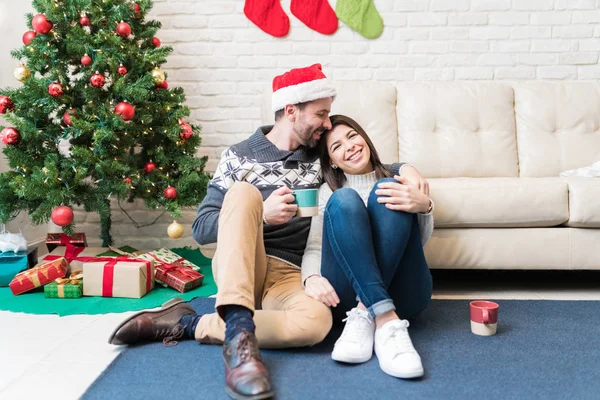 お祝いの季節に自宅でクリスマスツリーでコーヒーを飲みながら居心地の良いカップル — ストック写真