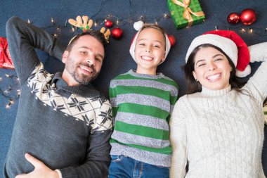 Gülümseyen anne baba ve oğulun Noel süslemeleri arasında yatışının genel görünümü