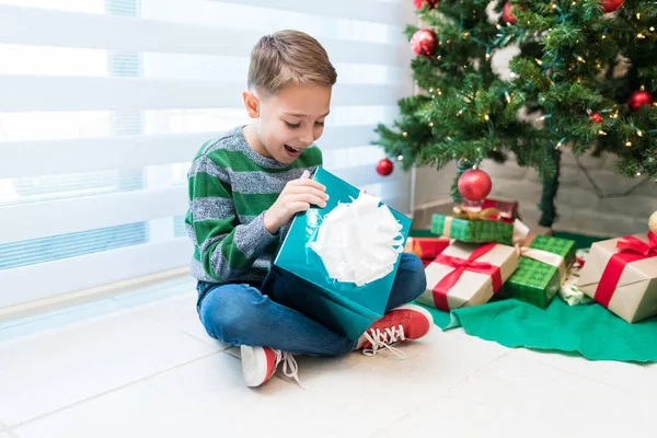 家で休日を祝いながらクリスマスプレゼントを見て幸せな興奮した子供 — ストック写真