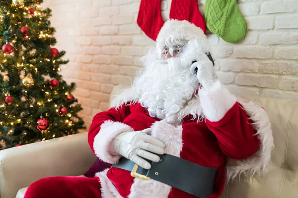 Święty Mikołaj Rozmawia Telefon Komórkowy Przez Choinkę Salonie Domu — Zdjęcie stockowe