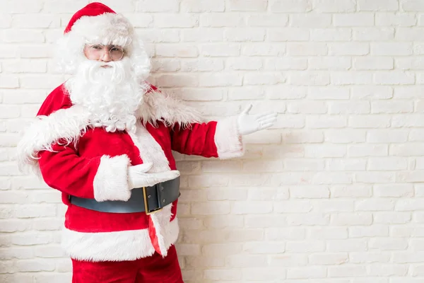 Santa Claus showing copy space over white brick wall at home