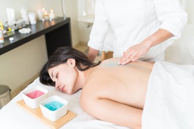 Beyaz masözün orta kesimi, sağlık merkezinde cilt bakımı sırasında kadının sırtını tedavi ediyor.