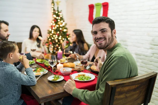 Happy male having meal with family at dining table during Christmas celebration