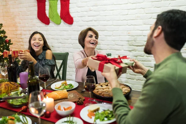 圣诞庆祝活动期间 快乐的家人在家中餐桌前互赠礼物 — 图库照片