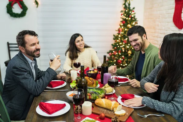 Smiling friends spending leisure time while having Christmas dinner during festive season at home