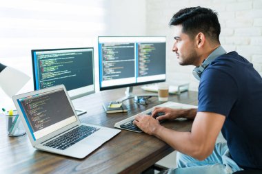 Evden çalışırken bilgisayar kullanan çekici İspanyol yazılım geliştirici programcılarının yan görünümü