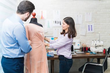 Çekici moda tasarımcısı ve iş arkadaşı tekstil stüdyosundaki kukla kumaşı inceliyor.