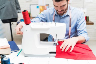 İspanyol terzi atölyedeki masada kumaş dikiyor.