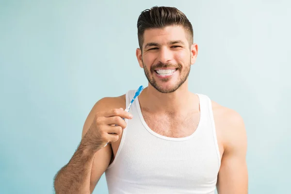 Привабливий Молодий Чоловік Посміхається Тримаючи Зубну Щітку Звичайному Тлі — стокове фото