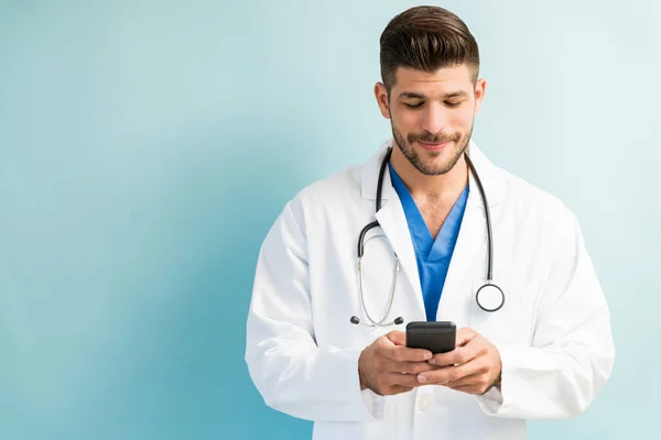 Ispanico Maschio Medico Sms Smartphone Mentre Piedi Sfondo Chiaro — Foto Stock