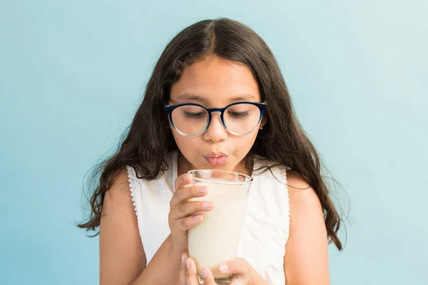 Preadolescent Female Child Blowing Hot Milk Glass Plain Background — Stock Photo, Image