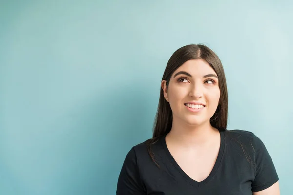 Mulher Bonita Olhando Embora Enquanto Pensa Contra Fundo Azul Turquesa — Fotografia de Stock