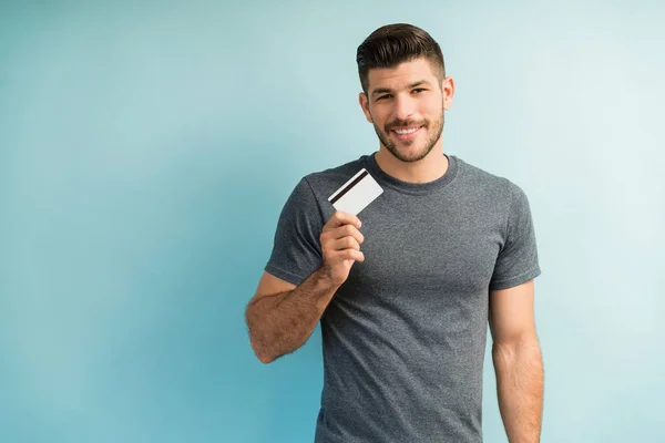Sonriendo Hombre Guapo Sosteniendo Tarjeta Crédito Mientras Hace Contacto Visual —  Fotos de Stock