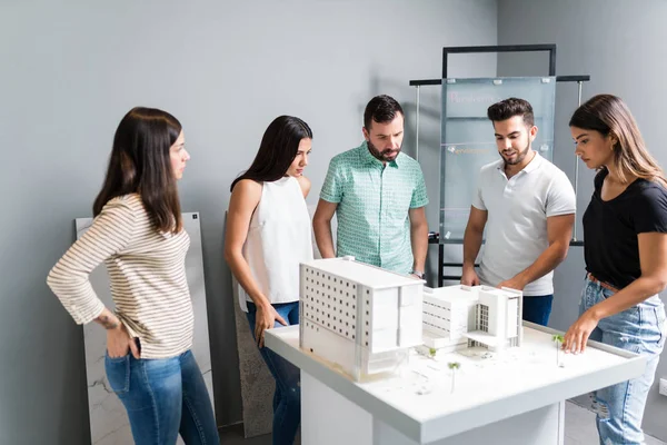 Male and female engineers discussing over model in architect office