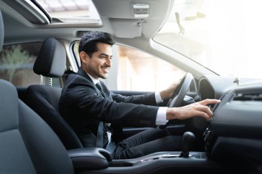 Araba sürerken müzik çalan gülümseyen genç iş adamının yan görüntüsü