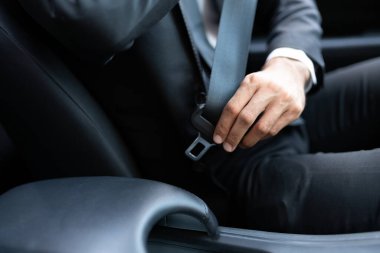 Arabada seyahat ederken emniyet kemerini ayarlayan iş adamlarının orta kısmı