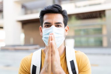 Elleri bağlı genç bir adam Coronavirus krizi sırasında yüz maskesi takmaya dikkat ediyor.