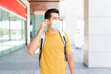 Coronavirus salgını sırasında şehirde maske takan genç adam gözlerini kaçırıyor.