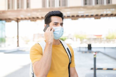 Koronavirüs salgını sırasında cep telefonuyla konuşan İspanyol genç adam gözlerini kaçırıyor.