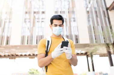 Latin genç adam Coronavirus krizi sırasında akıllı telefon kullanıyor.