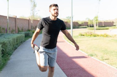Azimli İspanyol genç adam parkta yaya yolunda geriniyor.