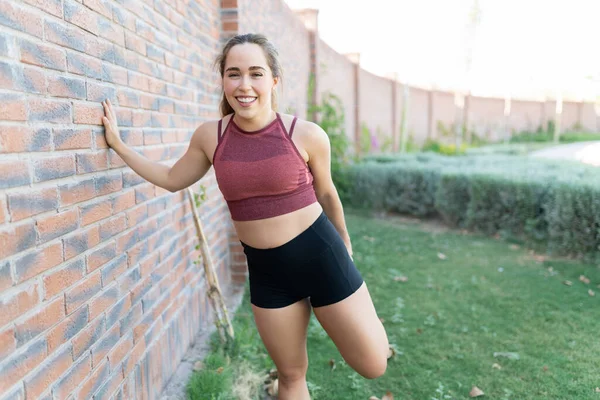 Atraktivní Usmívající Mladá Žena Dělá Zahřát Cvičení Cihlové Zdi Parku — Stock fotografie