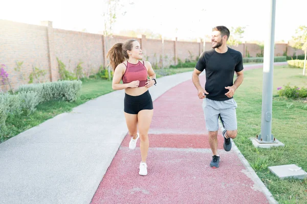 Parkta koşarken gülümseyen genç adam ve kadın.