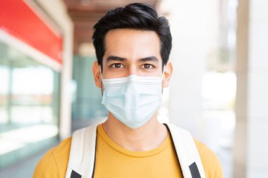 Coronavirus krizi sırasında yüz maskesi takan genç adamın yakın plan portresi.