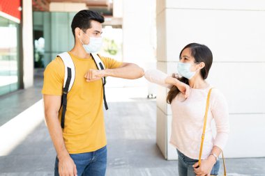 Koronavirüs salgını sırasında kadın ve erkek dirsek darbesiyle selamlaşıyorlar.