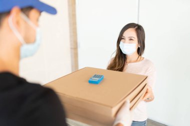 Coronavirus krizi sırasında teslimatçıdan paket alan yetişkin bir kadın.