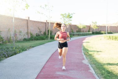 Atletik genç kadın parkta yaya yolunda koşuyor.