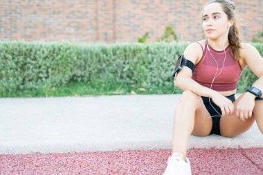 Parkta antrenman yaparken ara veren bitkin, genç bir bayan.