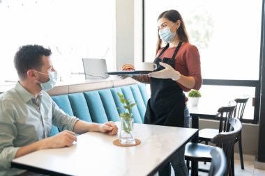 Restoranda Coronavirus salgını sırasında garsona bakan adam.