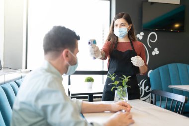 Personel, kahve dükkanındaki termal tarayıcıdan müşterinin vücut ısısını kontrol ediyor