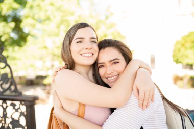 Gülümseyen genç arkadaşlar hafta sonu parkta birbirlerine sarılıyorlar.