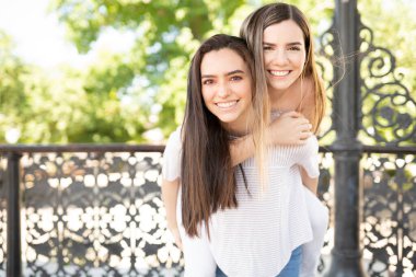 Gülümseyen genç bir kadın parkta arkadaşına sırnaşıyor ve birlikte eğleniyor.