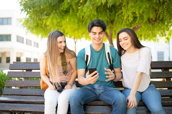 Jovem Hispânico Mostrando Smartphone Para Amigos Enquanto Sentado Parque Durante — Fotografia de Stock